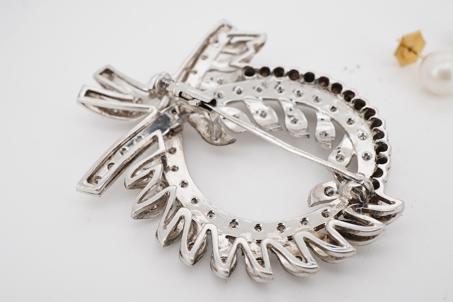 A white metal and diamond cluster set scrolling brooch, 52mm, together with a pair of yellow metal and cultured pearl set ear studs.